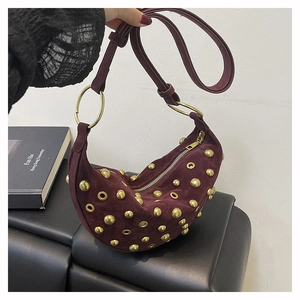 Détail du sac croissant en daim bordeaux avec clous dorés et anneaux métalliques