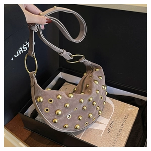 Détail du sac demi-lune en daim taupe avec clous dorés et accents d'oeillets métalliques