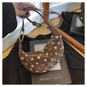 Détails du sac hobo en daim marron avec des rivets dorés et des anneaux métalliques