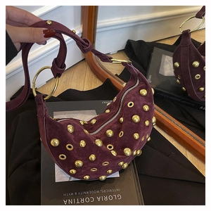 Détail du sac hobo en daim bordeaux avec rivets dorés et décorations d'œillets