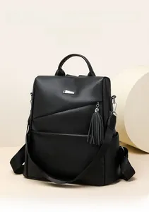Detail eines schwarzen Lederrucksacks mit Kieselstruktur, Silberdeko und Quastenanhänger