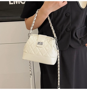 Dettaglio borsa a tracolla trapuntata beige con catena argento e chiusura a girello in metallo