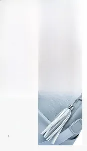 Detail eines hellblauen Lederrucksacks mit silbernen Beschlägen und weißem Quasten-Zipper