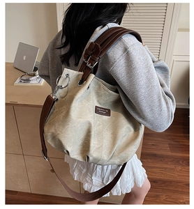 Detail of khaki canvas tote bag with leather straps worn by model in an office setting
