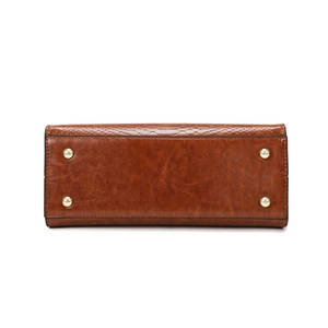 Bottom view of brown leather handbag featuring four gold metal protective feet and embossed texture