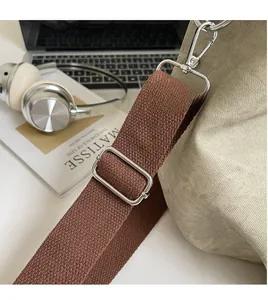 Detail of adjustable brown woven shoulder strap with silver metal hardware on canvas bag