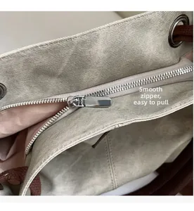 Detail view of smooth silver metal zipper and pink fabric lining on beige tote bag