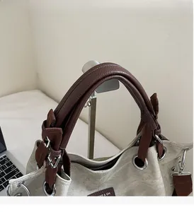 Detail of durable brown leather handles and beige canvas on this large tote handbag