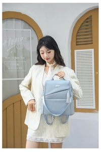 Detail eines hellblauen Rucksacks aus strukturiertem Leder mit Quaste und Silberbeschlägen