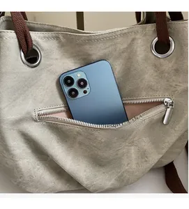 Detail of canvas tote bag with functional silver zipper pocket holding a large smartphone