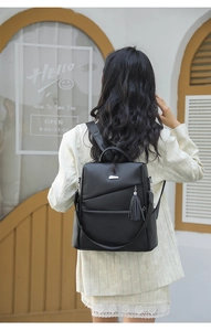 Detailansicht des schwarzen Rucksacks aus Leder mit Quaste und silberner Logo-Plakette