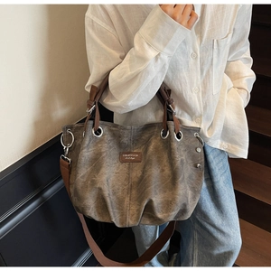 Close-up of vintage pleated tote bag showing washed canvas texture and leather logo tag