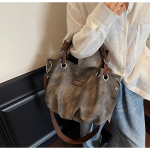Detail of vintage tote bag featuring silver eyelets, studs, and brown shoulder strap