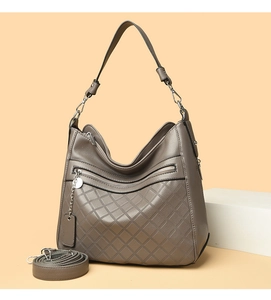 Detail view of taupe leather bag with quilted pattern, metal chain, and adjustable straps