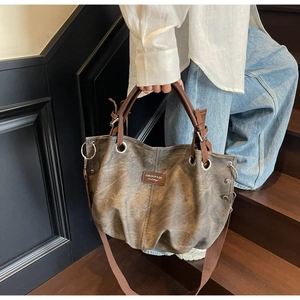 Detail view of vintage dark taupe tote bag with leather handles and metallic rivets