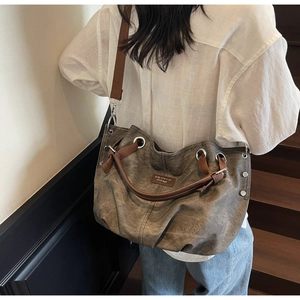 Detail view of large vintage tote bag with leather handles and metallic eyelet accents