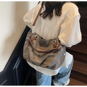 Detail of vintage grey canvas tote bag with brown leather handles and silver metal rivets