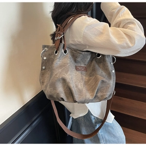 Detail of washed canvas tote bag with brown leather handles on a model in a staircase