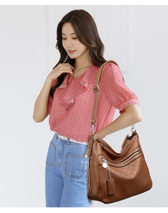 Detail of vintage brown leather bag featuring quilted texture and silver zipper pendant
