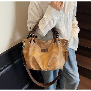 Dettaglio della borsa tote vintage caramello con occhielli in metallo e patch in pelle