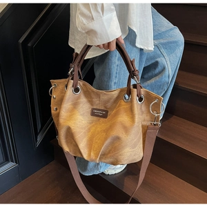 Detail shot of vintage tote bag with wide shoulder strap and leather texture on stairs
