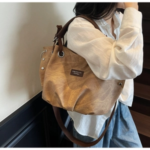 Detailed side view of vintage brown tote bag with metal eyelets and wide shoulder strap