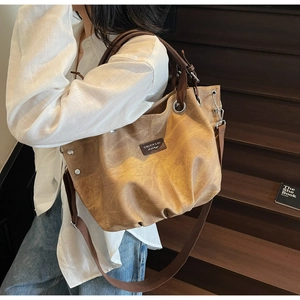 Vista dettagliata della borsa tote retrò con logo e manici in pelle marrone sulla spalla