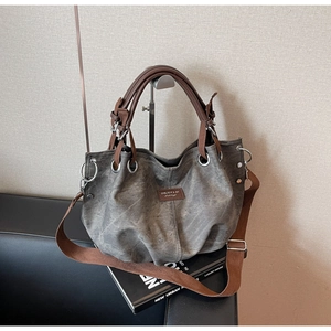 Detail of vintage tote bag with metal ring, brown handles, and wide shoulder strap