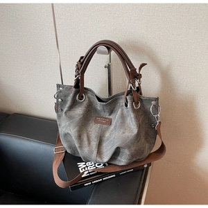 Macro view of grey vintage tote with brown leather handles and textured shoulder strap