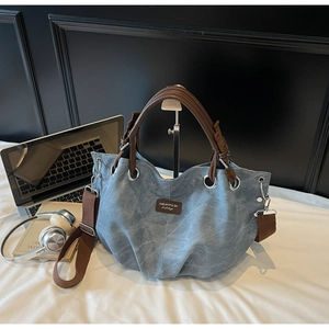 Dettaglio borsa tote blu lavato con manici in pelle marrone e patch in pelle logato