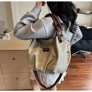 Borsa tote retrò in tela kaki con manici in pelle e borchie argentate in un ambiente moderno