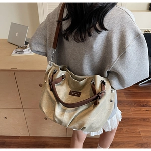 Dettaglio della borsa tote in tela kaki con tracolla in pelle marrone e occhielli in metallo