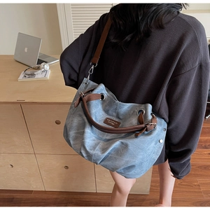 Dettaglio della borsa hobo in tela azzurra con spalline marroni e occhielli in metallo retrò