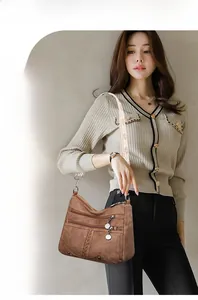Detail of dark brown soft leather crossbody bag with ethnic style embroidered shoulder strap