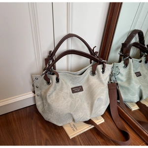 Macro detail of canvas tote bag with brown leather handles and wide fabric strap