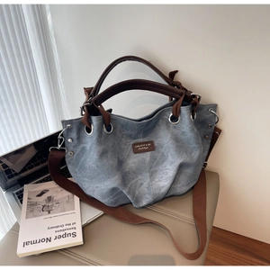 Dettaglio della borsa tote in tela lavata blu con manici in pelle e borchie metalliche