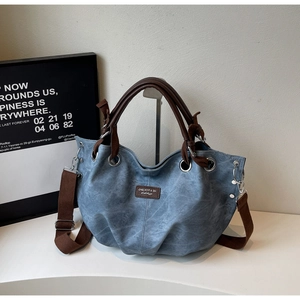 Detail showing blue canvas tote texture with brown strap and metallic eyelets on the bag