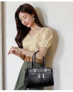 Detail of black pebbled leather tote bag with silver zippers and multi-pocket design