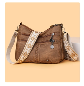 Detail of vintage brown soft leather bag featuring multiple zipper pockets and floral strap