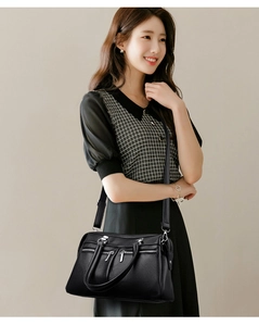 Detail of black pebbled leather texture and silver zippers on a versatile tote bag