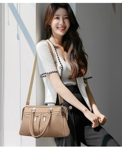 Detail of khaki leather handbag featuring multiple zip pockets and detachable wide strap