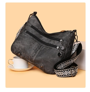 Detail of dark grey crossbody bag with multiple zip pockets and ethnic woven strap