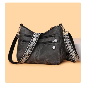 Detail of dark gray soft leather bag with multi-zipper pockets and geometric woven strap