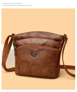Détail du sac bandoulière en cuir marron avec plusieurs fermetures éclair et rivets