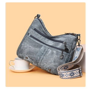 Detail of grey-blue canvas crossbody bag with multi-zipper pockets and jacquard star strap