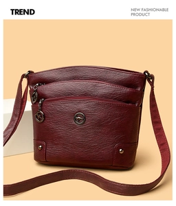 Détails du sac en cuir souple bordeaux montrant trois fermetures éclair et logo en métal