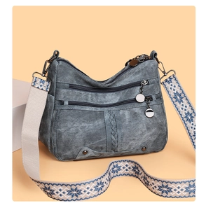 Detail view of smoky grey crossbody bag with multiple zippers and patterned strap