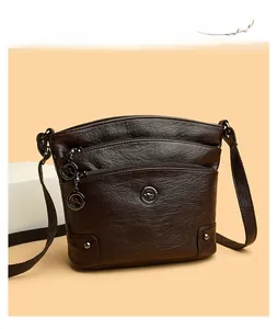 Détail de la texture cuir marron foncé et des poches zippées multicouches sur le sac