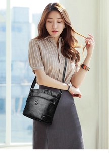 Détail du sac bandoulière en cuir grainé noir avec plusieurs zips et boucles argentées