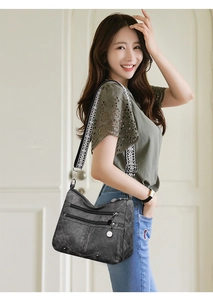 Detail of grey soft leather crossbody bag with multiple zippers and jacquard strap